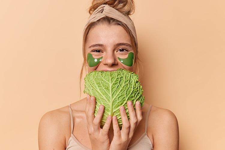 positive-young-woman-uses-natural-products-skin-care-holds-cabbage-mouth-wears-green-hydrogel-patches